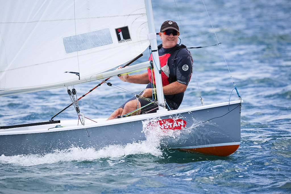 Shaun McKenna sailing his Sabre dinghy upwind at the 45th Australian Sabre Championship, McCrae Yacht Club, looking at camera