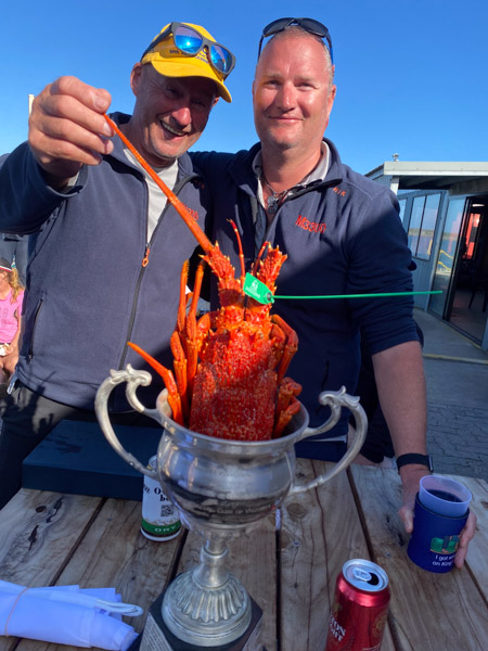 Andrew McGrath and Ben Thompson with the Grassy Perpetual Trophy Andrew McGrath and Ben Thompson with the Grassy Perpetual Trophy and a King Island crayfish at the 2025 ORCV Melbourne to King Island Race presentation, King Island Boat Club, Grassy Harbour, Tasmania