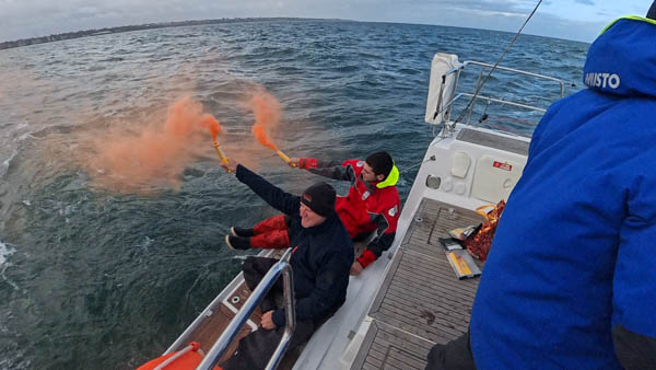 Orange smoke distress flare being deployed from the swim platform of Shimmer during the ORCV live flare demonstration on Port Phillip Bay.