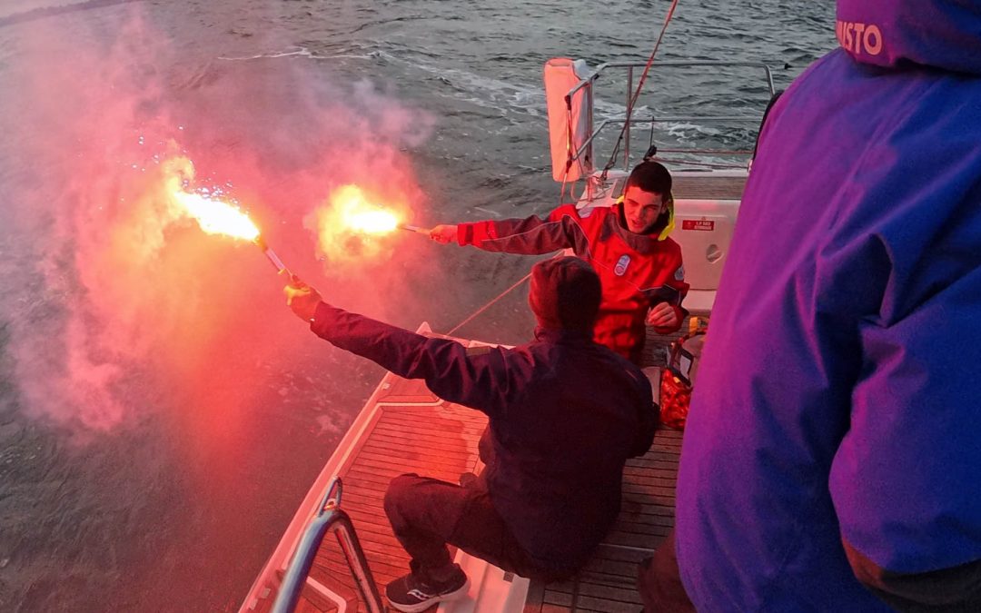 Crew members aboard Shimmer firing handheld red marine distress flares during the ORCV Winter Series safety flare demonstration on Port Phillip Bay.