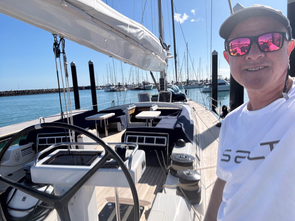 Bowman Shaun McKenna selfie from the starboard quarter of Swan 82 Crackerjack V looking forward along the deck and twin helm wheels.