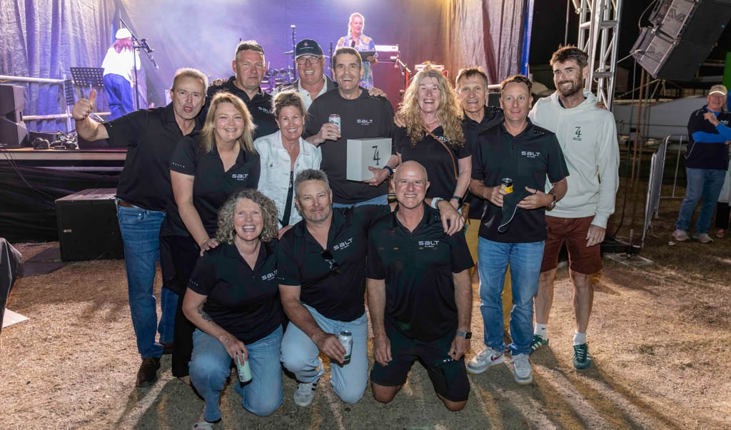 Crew of Solaris 50 Salt standing in front of the stage receiving their 2nd place trophy at Airlie Beach Race Week 2026.