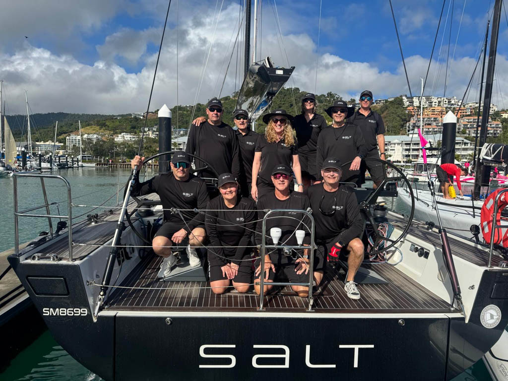 Crew of Solaris 50 Salt gathered on the stern looking at the camera, with transom displaying boat name Salt in the foreground.